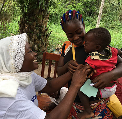 Annie Ayoko (left) cheers up a baby to whom she has just subministrated a vaccine. © T. Baldassarri Höger von Högersthal / Interholco. All rights reserved.